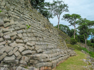 Photo of long wall of stones with those in the foreground scattered and jumbled.